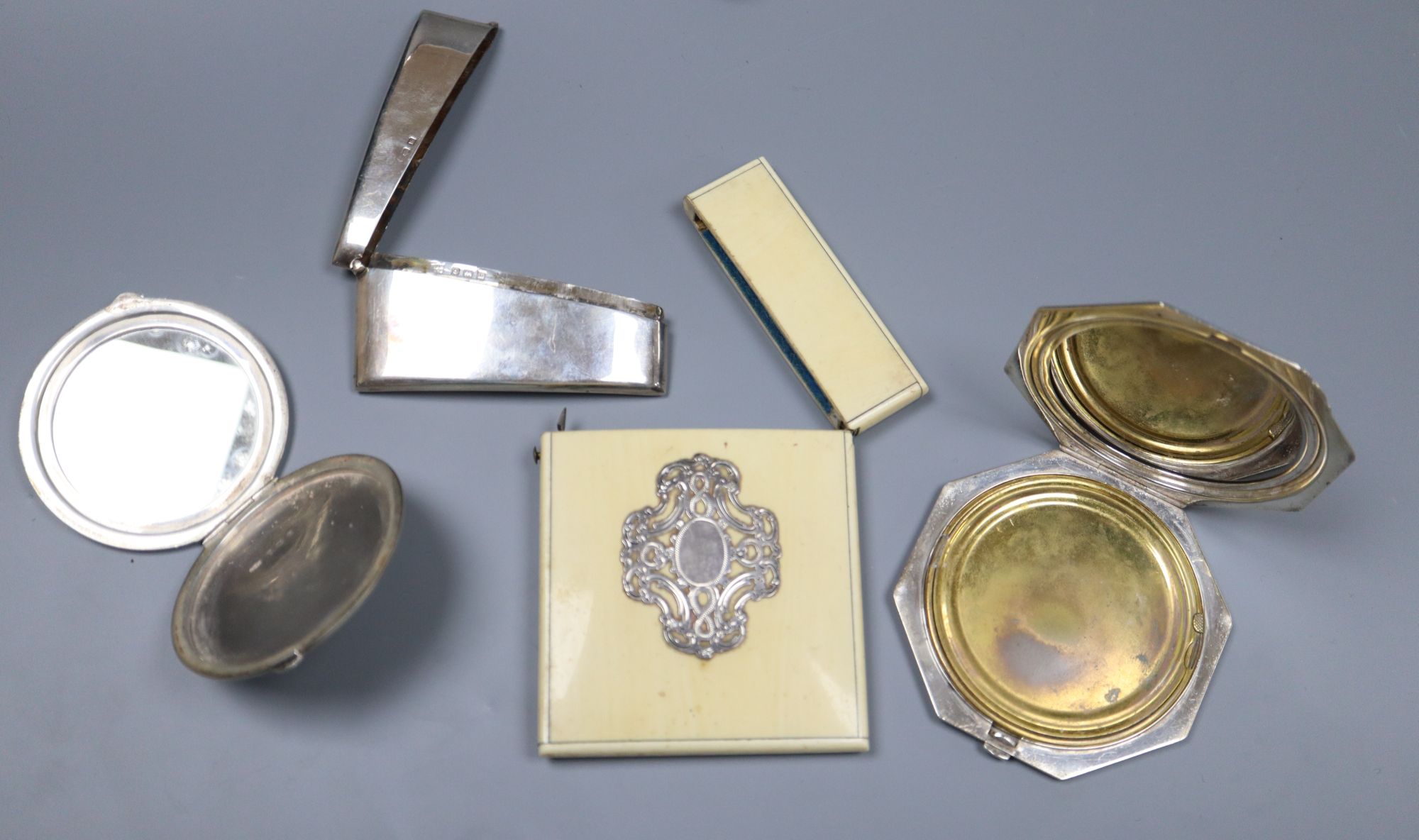 A George V silver concave card case, 82mm, two silver compacts and an ivory card case